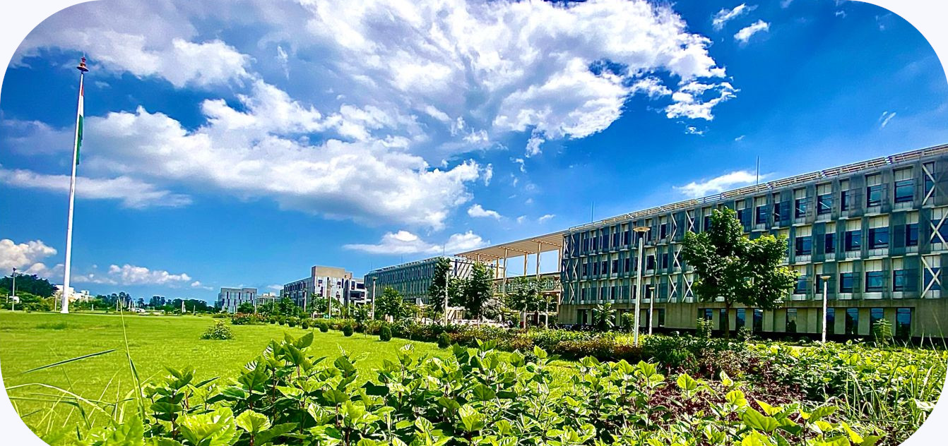 The IIT Ropar campus — academic buildings and green lawns beneath a bright monsoon sky, with the Indian flag on a tall mast